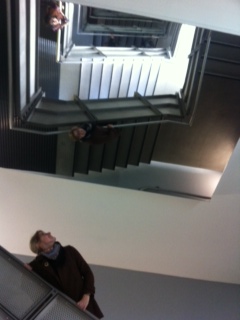a woman looks up towards a staircase filled with mirrors